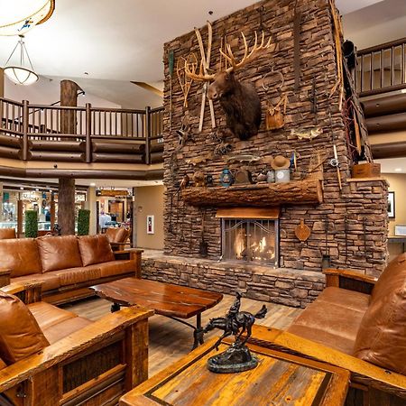 فندق ذا جراند آت جراند كانيون توسايان المظهر الخارجي الصورة The photo shows a cozy lodge-style interior with a warm, inviting atmosphere. The focal point is a large stone fireplace with a mounted deer head above it. Surrounding the fireplace are comfortable leather sofas and wooden furniture, creating a rusti