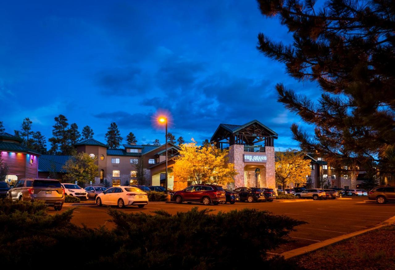 فندق ذا جراند آت جراند كانيون توسايان المظهر الخارجي الصورة The photo shows a hotel or lodge building during twilight, with a blue sky and clouds. There are several cars parked in front, and some illuminated trees add warmth to the scene. The architecture features a combination of stone and wood elements, and
