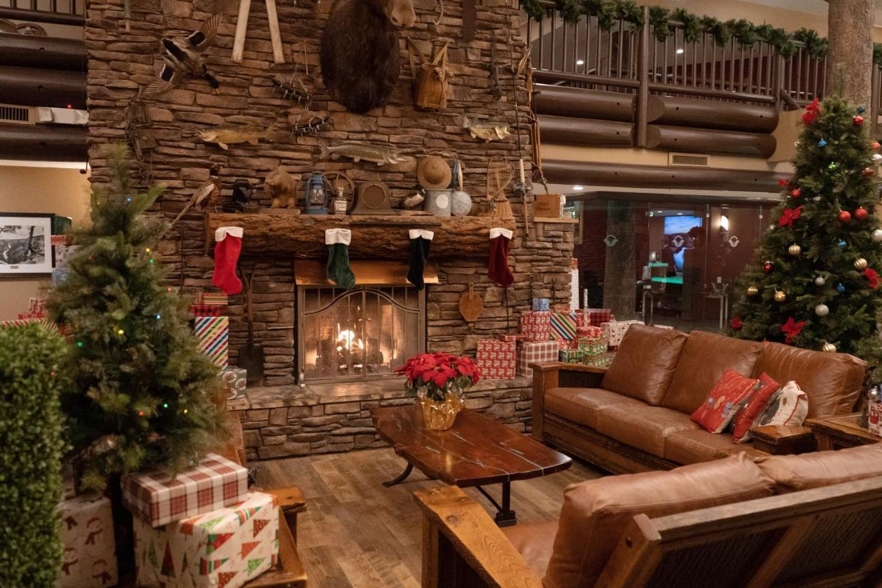 فندق ذا جراند آت جراند كانيون توسايان المظهر الخارجي الصورة The photo depicts a cozy interior setting, likely a lodge or cabin, decorated for the holiday season. In the center, there is a stone fireplace with a roaring fire, adorned with festive stockings hanging from the mantel. Above the fireplace, there ar