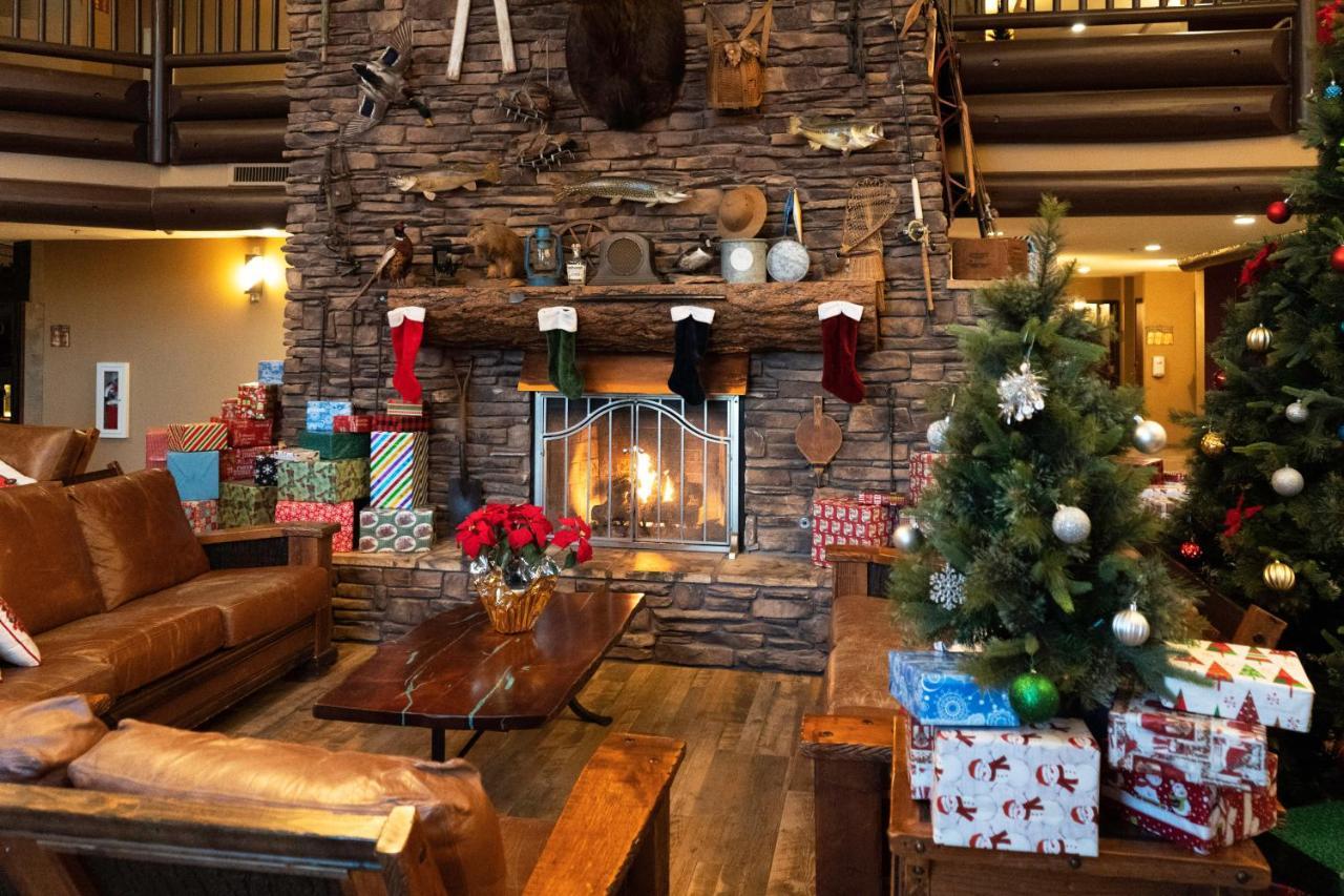 فندق ذا جراند آت جراند كانيون توسايان المظهر الخارجي الصورة The photo depicts a cozy lodge-like interior, highlighted by a large stone fireplace at the center. Above the fireplace, there are various decorative items, including fishing gear and a mounted animal head. The fireplace is adorned with colorful Chri
