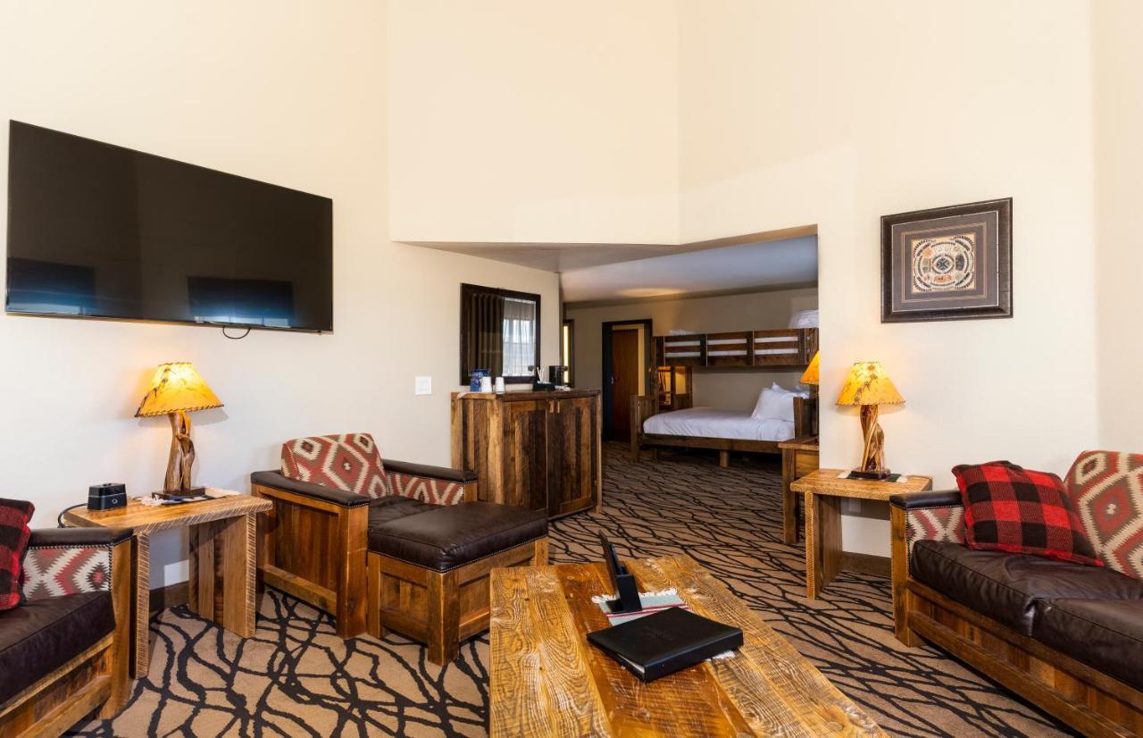فندق ذا جراند آت جراند كانيون توسايان المظهر الخارجي الصورة The photo shows a cozy living area of a hotel or lodge. It features rustic wooden furniture, including armchairs and a coffee table. A large flat-screen TV is mounted on the wall. There are lamps with warm lighting and decorative patterns on the furn