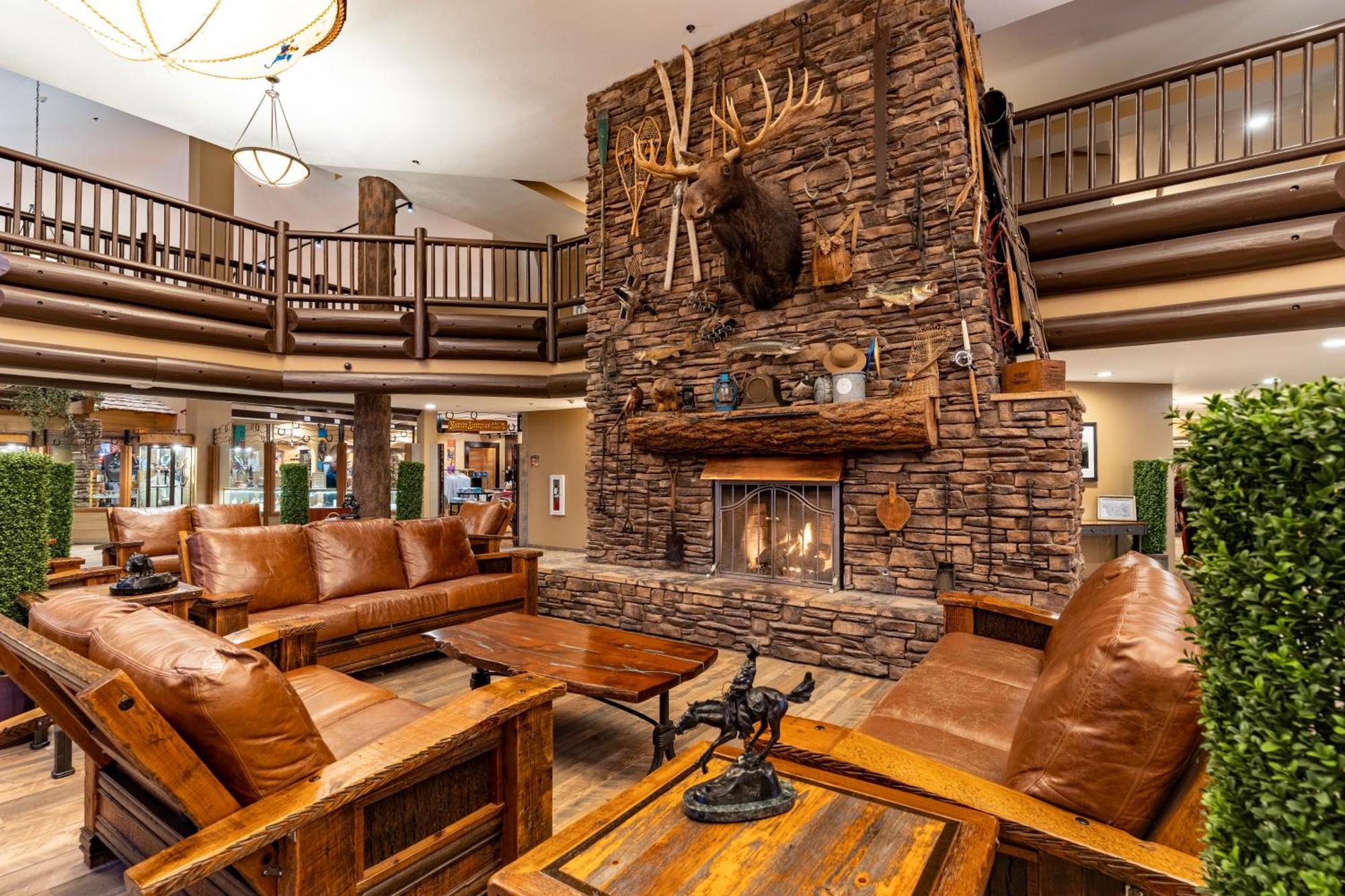 فندق ذا جراند آت جراند كانيون توسايان المظهر الخارجي الصورة The photo shows a cozy lodge-style interior with a warm, inviting atmosphere. The focal point is a large stone fireplace with a mounted deer head above it. Surrounding the fireplace are comfortable leather sofas and wooden furniture, creating a rusti
