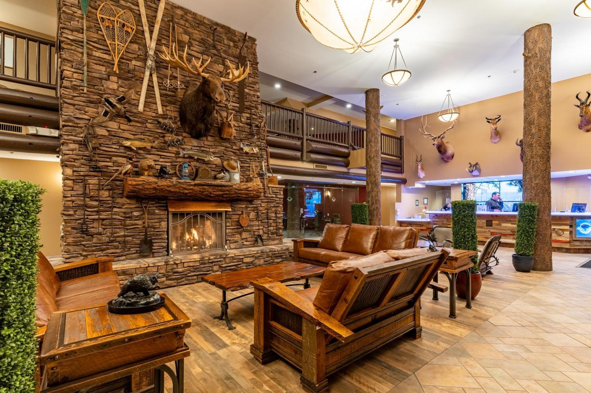 فندق ذا جراند آت جراند كانيون توسايان المظهر الخارجي الصورة The photo shows a cozy lobby area with a rustic design. A large stone fireplace is the focal point, adorned with a mounted animal head and various decorative items like snowshoes and antlers. The seating consists of wooden furniture, including a coup
